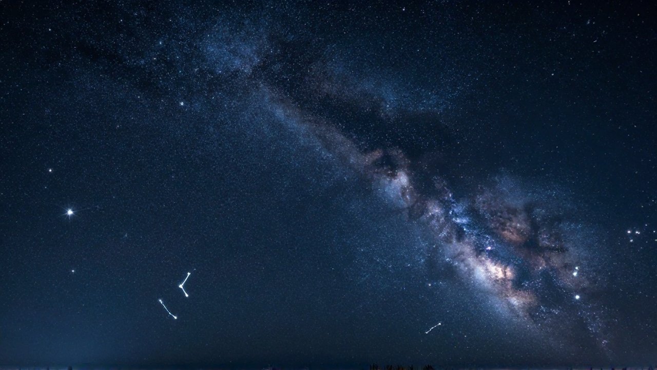 Vasto cielo nocturno de verano con constelaciones brillantes y la Vía Láctea extendiéndose sobre el espacio.