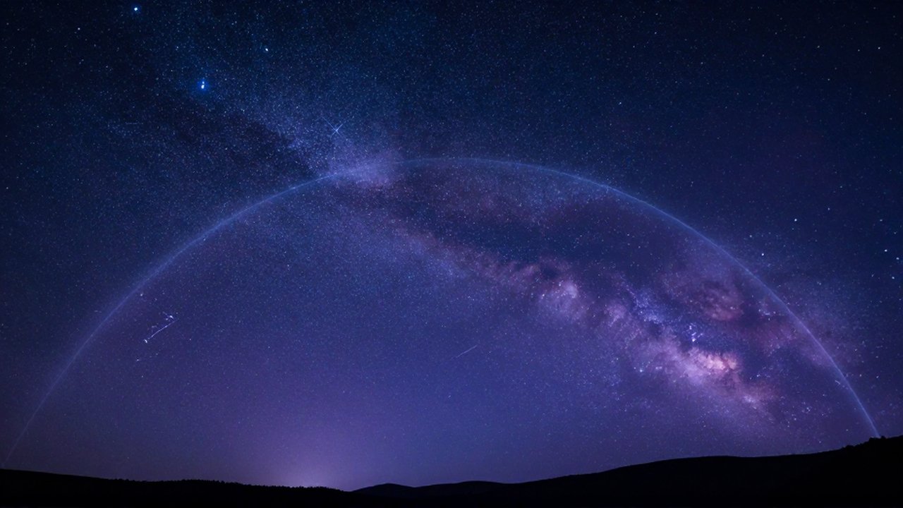 Cielo nocturno estrellado dividido por el ecuador celeste sobre la silueta de una montaña oscura.