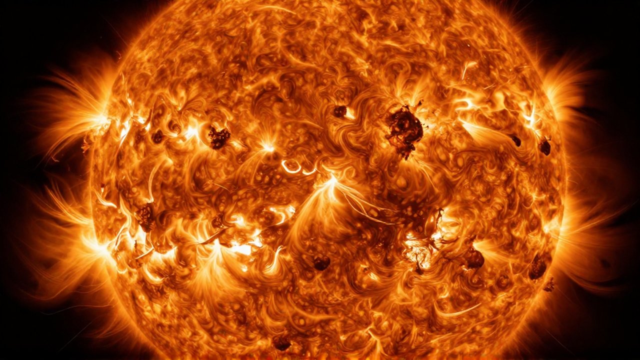 Superficie dorada y rugosa del Sol con manchas oscuras y llamaradas de plasma incandescente.